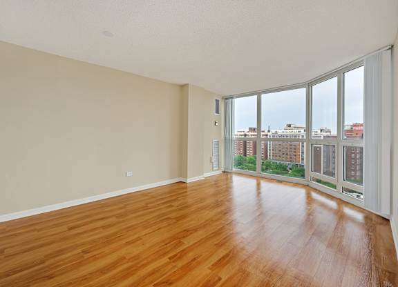 Empty room with wooden floors and large windows.