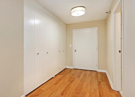 A hallway with a white door and wooden floors.
