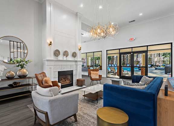 A living room with a fireplace, a blue couch, and a round mirror.
