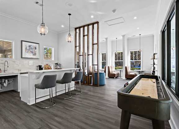 A billiard table is in the middle of a room with a bar and chairs.