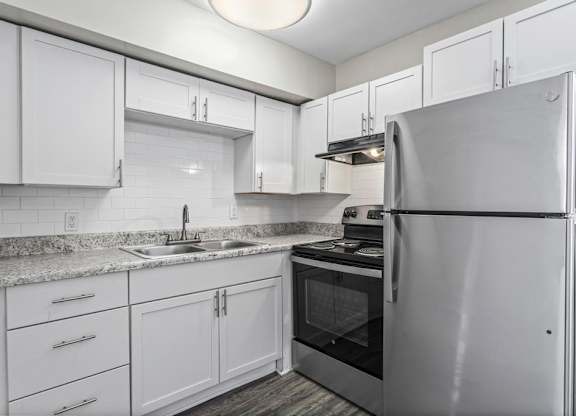 a kitchen with white cabinets and a stainless steel refrigerator