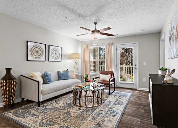 A living room with a couch, a coffee table, and a ceiling fan.