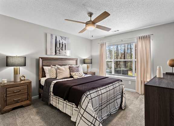 A bedroom with a bed, nightstand, and a ceiling fan.