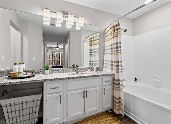 A bathroom with a white tub, sink, and shower curtain.