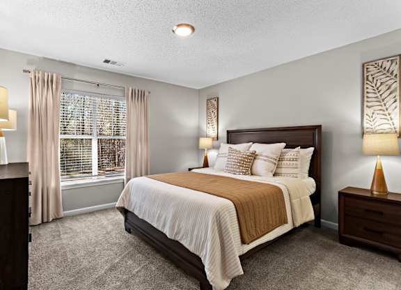 A bedroom with a large bed and a window with curtains.