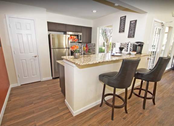 a kitchen with a breakfast bar and a stainless steel refrigerator