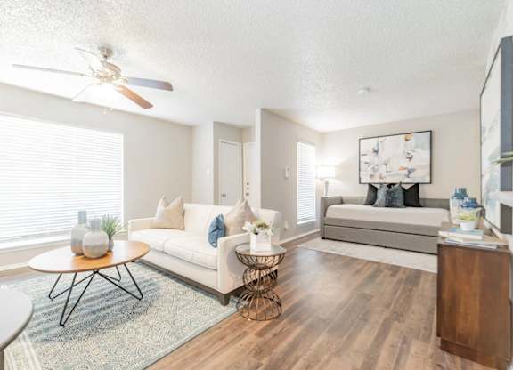 a spacious living room with a ceiling fan and hardwood flooring