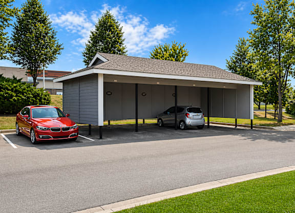 A red car is parked in front of a white garage.