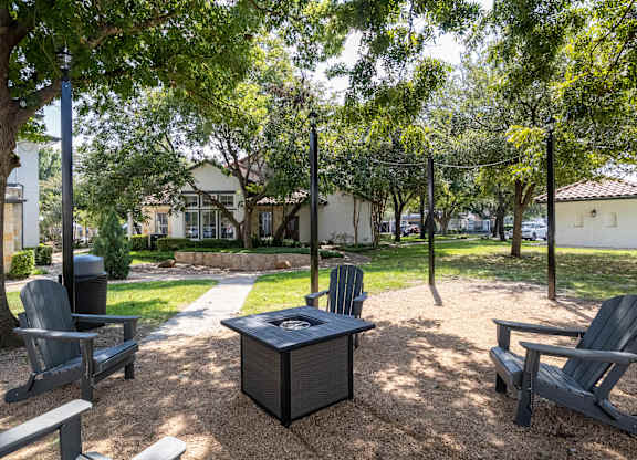 A park with a table and chairs under a tree.