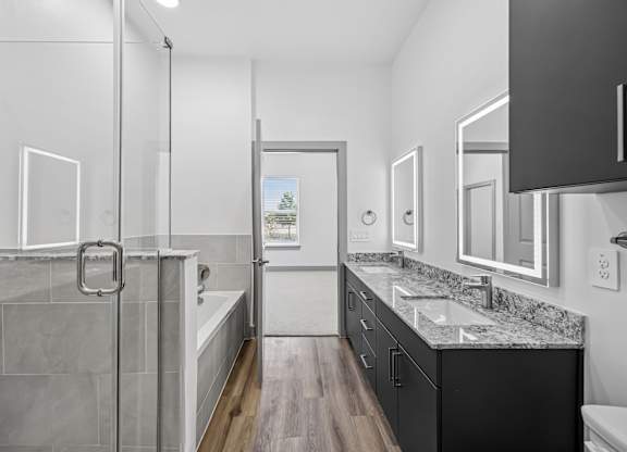 A bathroom with a walk-in shower and a vanity with a marble countertop.