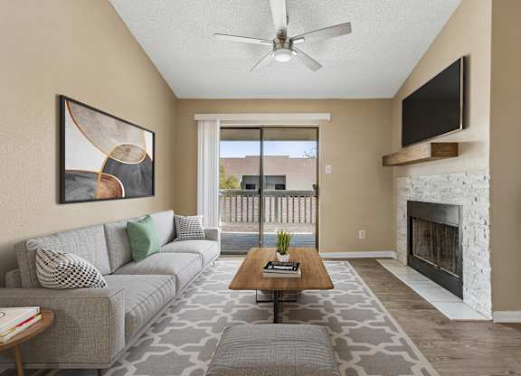 A living room with a grey couch, a coffee table, a fireplace, and a painting on the wall.