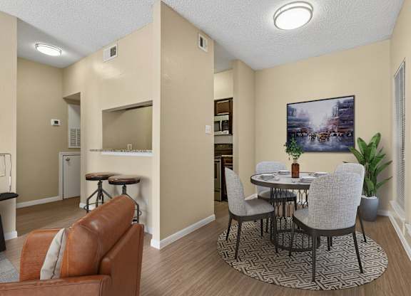 A living room with a brown leather couch and a round table with chairs.