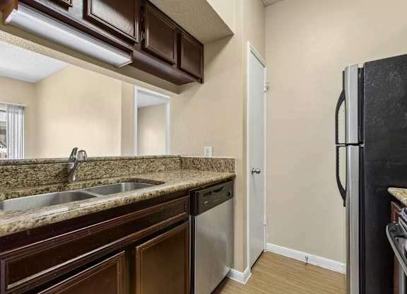A kitchen with brown cabinets and a black refrigerator.