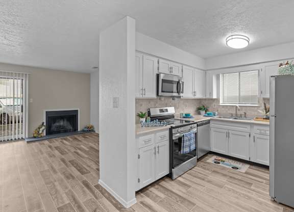 A kitchen with white cabinets and a wooden floor.