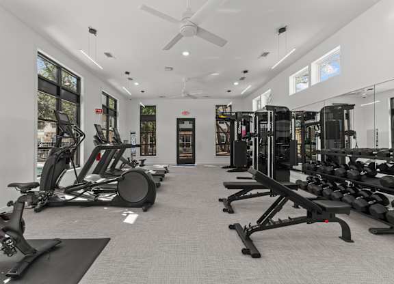 A gym with a variety of equipment including treadmills, stationary bikes, and weight machines.