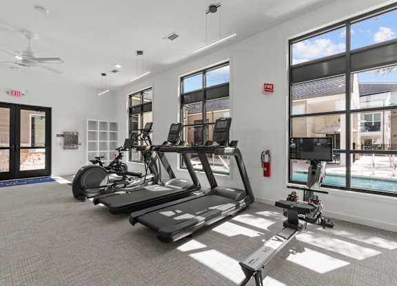 A gym with treadmills, exercise bikes, and a television.