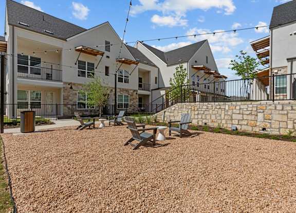 A gravel courtyard with a picnic table and chairs in front of apartment buildings.