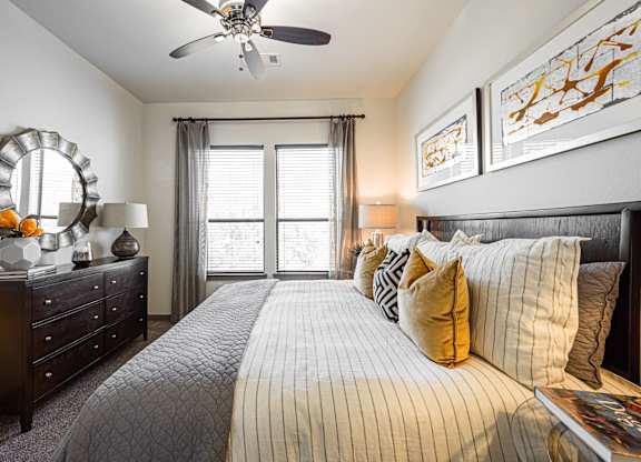 A bedroom with a large bed, a dresser, and a ceiling fan.