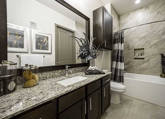 A bathroom with a marble countertop and a white bathtub.
