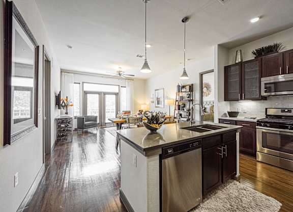 A modern kitchen with dark wood floors and stainless steel appliances.