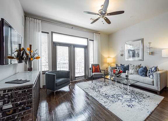 A living room with a grey sofa, a coffee table, and a ceiling fan.