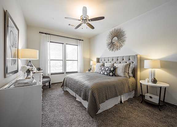 A bedroom with a large bed and a ceiling fan.