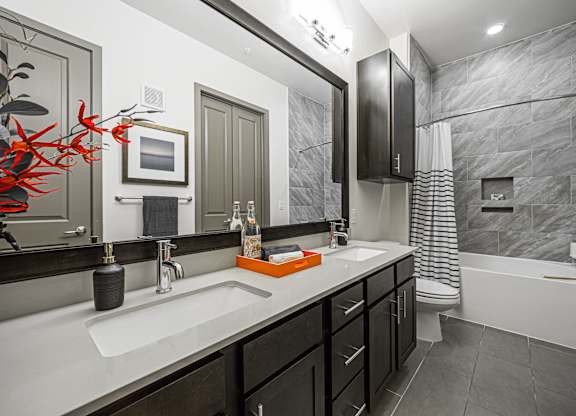 A bathroom with a sink, mirror, and bathtub.