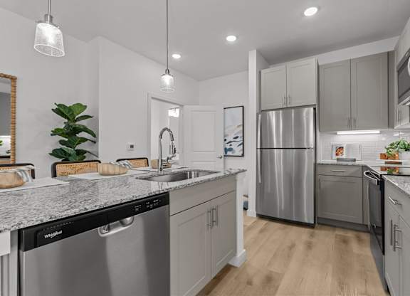 A modern kitchen with stainless steel appliances and wooden floors.