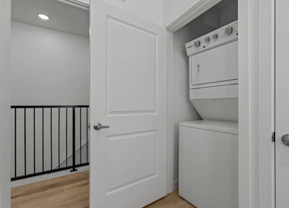 A white door is open to a small kitchen with a white oven.
