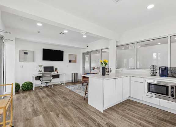 A modern kitchen with white cabinets and a wooden floor.