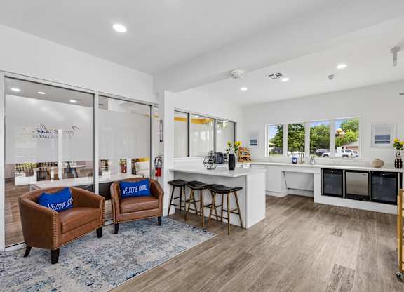 A modern kitchen with brown chairs and a blue rug.
