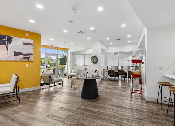 A modern living room with a yellow accent wall and a variety of seating options.