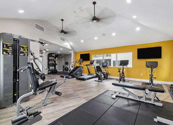 A spacious gym with a variety of equipment including treadmills, stationary bikes, and weight machines.