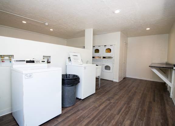 A kitchen with white appliances and wood floors.