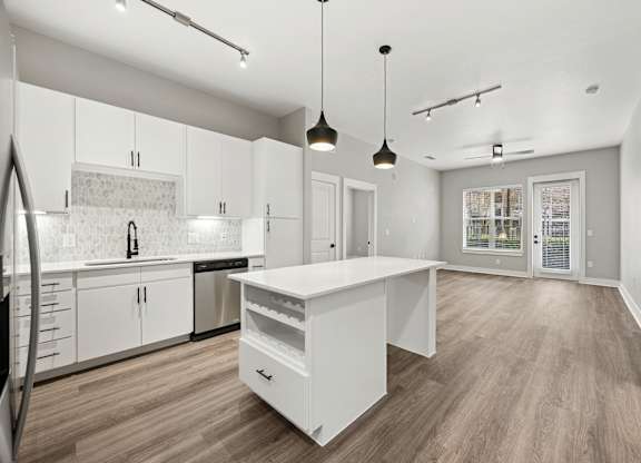 A modern kitchen with a white island and wooden floors.