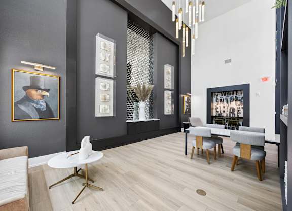 A modern living room with a grey couch, a white coffee table, and a painting of a man in a hat.