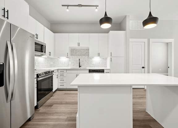 A modern kitchen with white cabinets and a large island.
