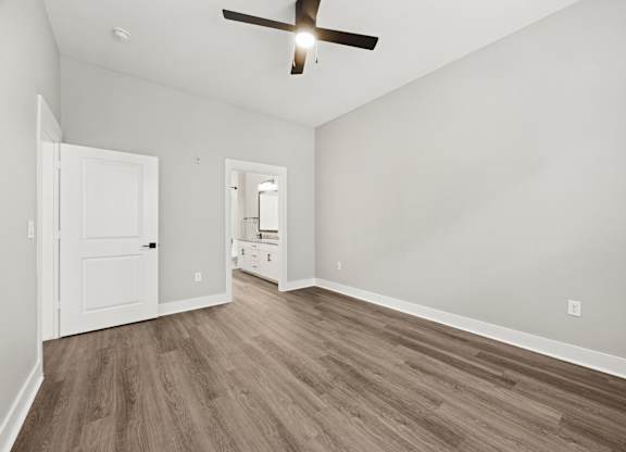 A room with a ceiling fan and wood flooring.