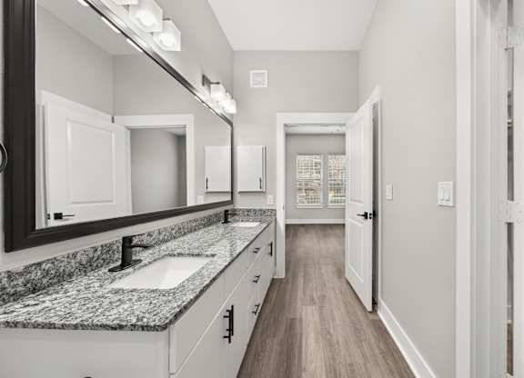 A bathroom with a marble countertop and white cabinets.