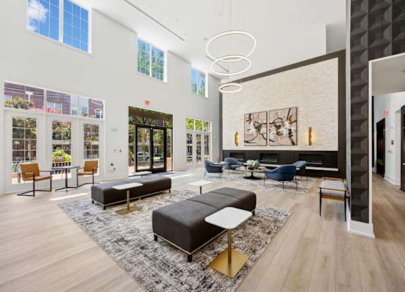 A modern living room with a black and white rug and a large black couch.