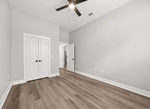 A room with a ceiling fan and wooden flooring.