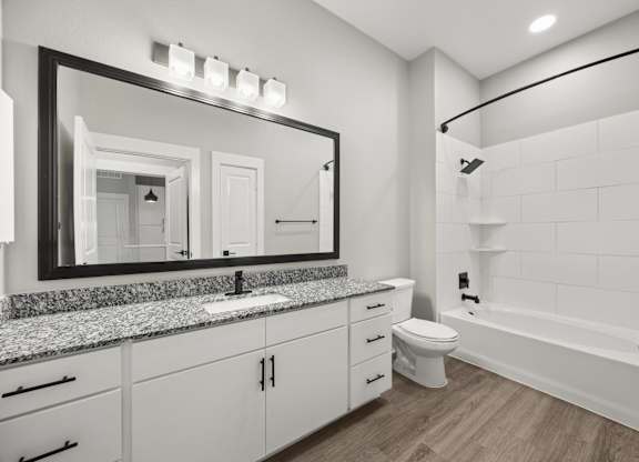 A bathroom with a large mirror, sink, toilet, and bathtub.