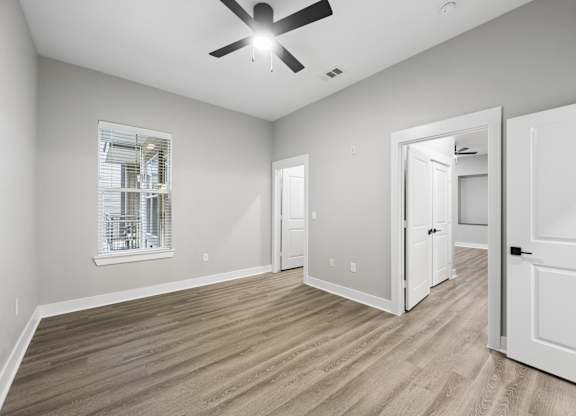 A room with a ceiling fan and a window with blinds.
