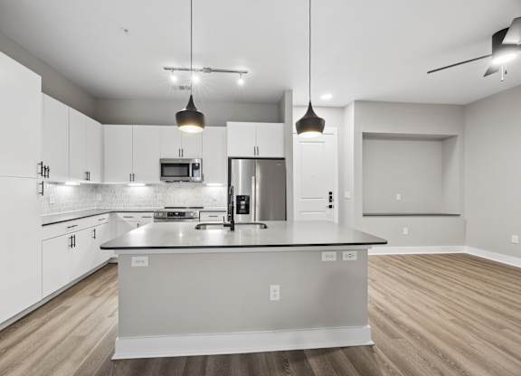 A modern kitchen with a large island and pendant lights.