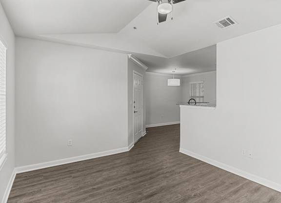 an empty living room and kitchen with white walls and wood flooring