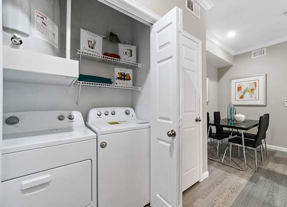 a laundry room with a washer and dryer and a dining room table with chairs