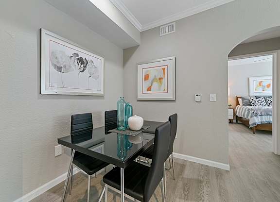 a dining area with a glass table and four black chairs