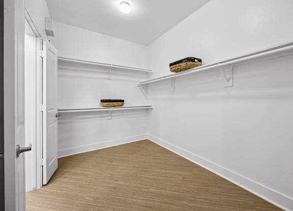 A white room with a wooden floor and a door on the left.