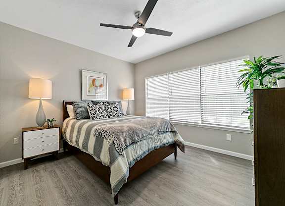 a bedroom with a large window and a ceiling fan