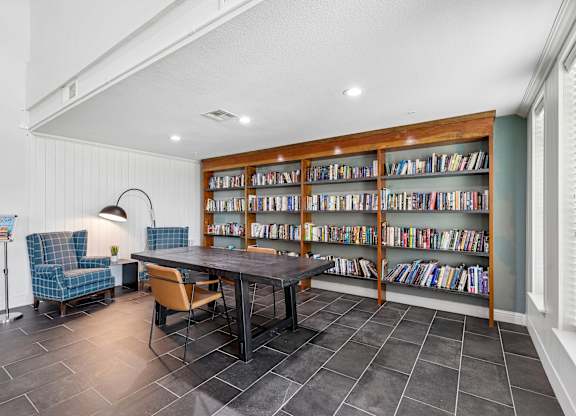 A room with a table, chairs and a bookshelf.